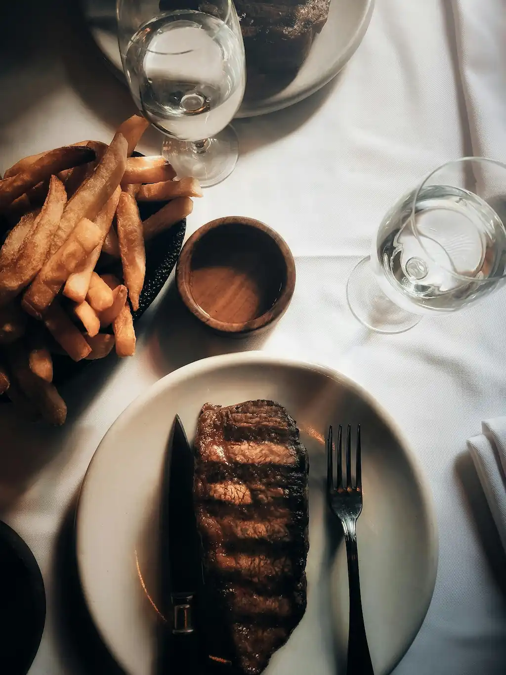 Juicy steak served with crispy thick oven-baked steak fries on a dining table